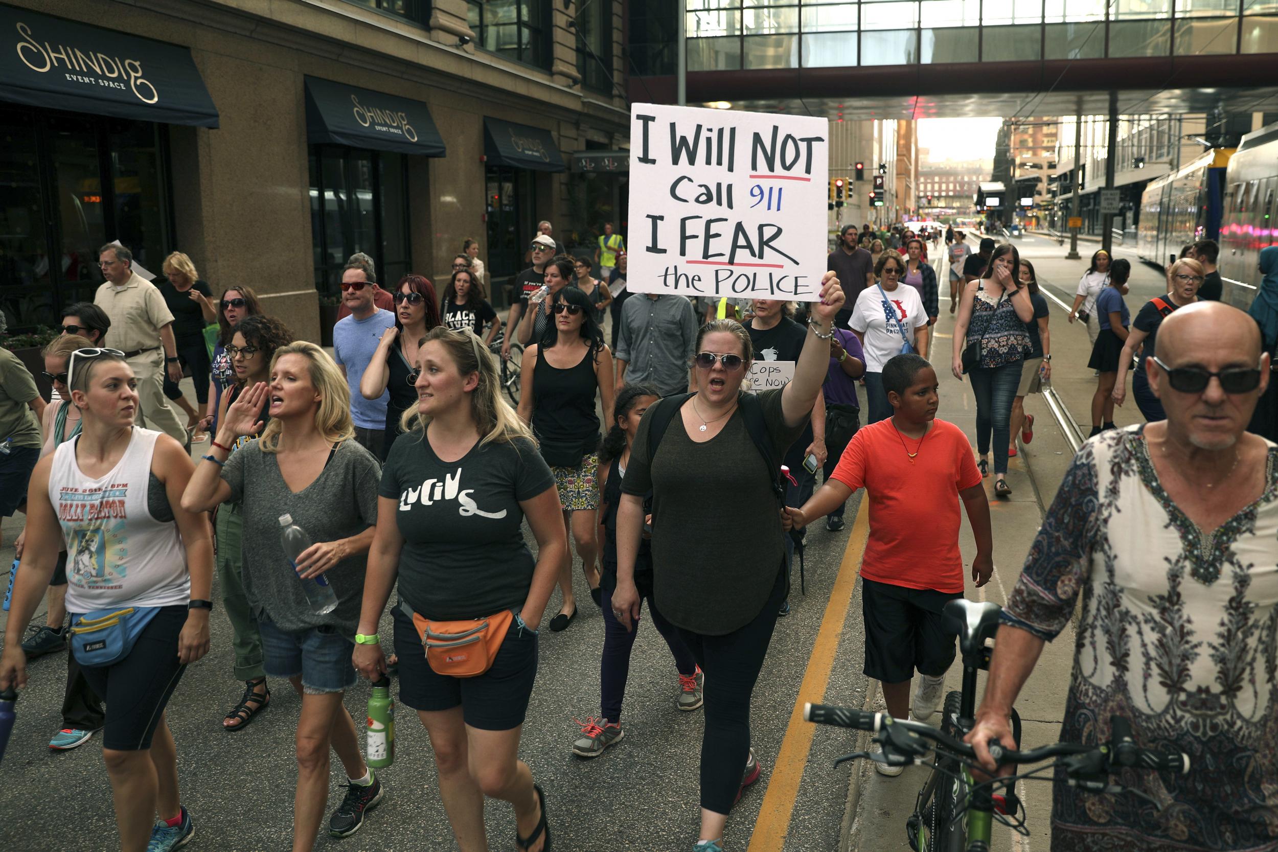 A protester holds a sign as she participates in a march against police violence following the fatal shooting by an officer of unarmed Australian woman Justine Damond