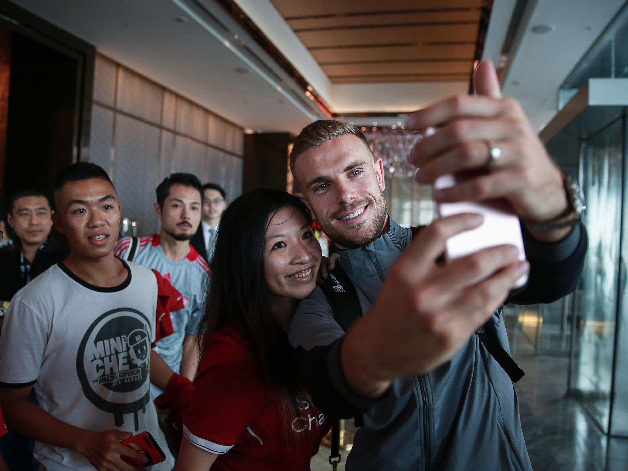 Jordan Henderson poses with a fan in Hong Kong