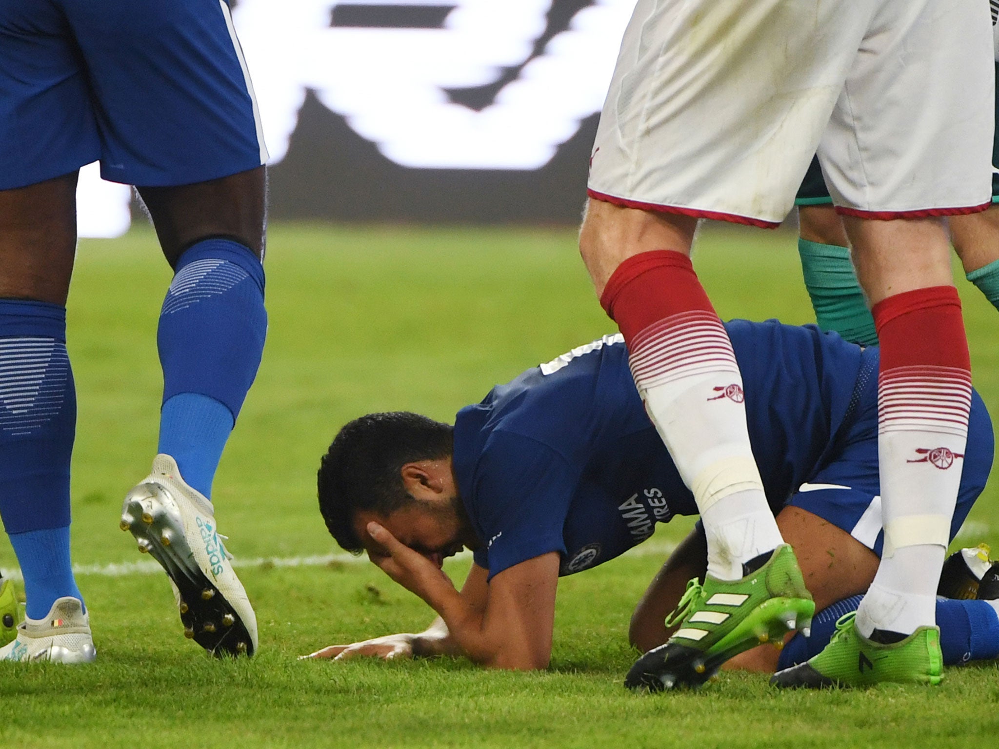 Pedro holds his head after colliding with Arsenal 'keeper David Ospina