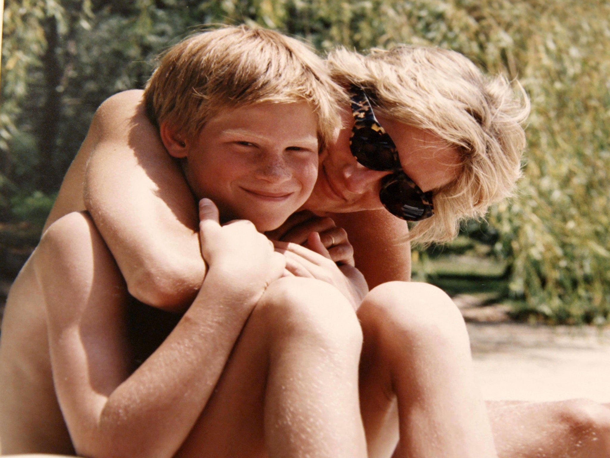 An undated handout picture released by Kensington Palace from the personal photo album of the late Diana, Princess of Wales shows her embracing Prince Harry while on holiday at an undisclosed location