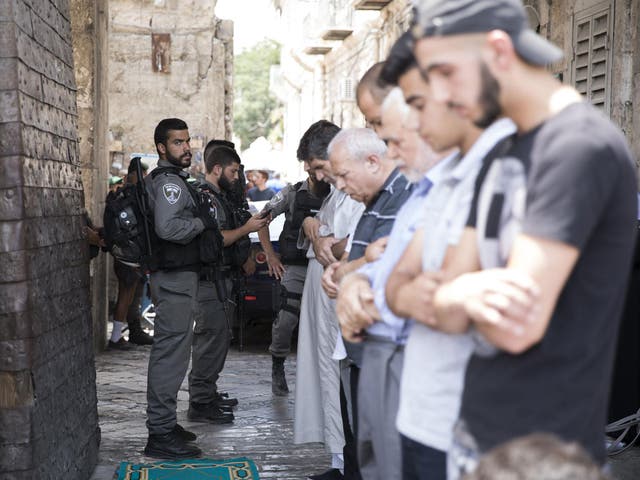 Israeli border police on duty as Palestinians pray at the Lion's Gate in the Old City of Jerusalem near the entrance to the Noble Sanctuary or Temple Mount, at the Old City of Jerusalem
