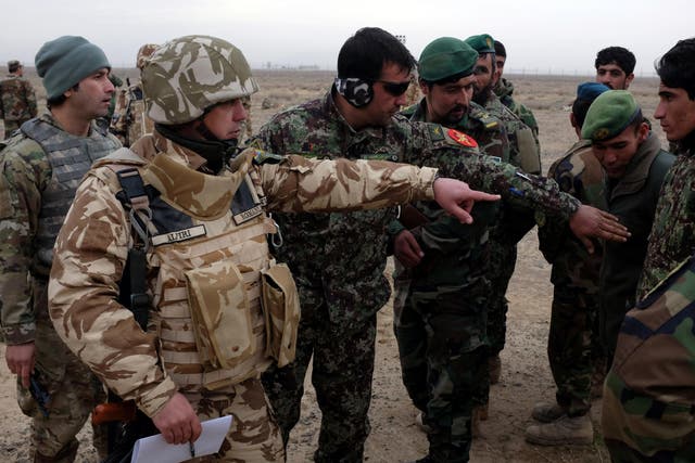 A Romanian military adviser speaks with Afghan troops during a live-fire artillery exercise outside Kandahar Air Field in this file photo from 15 February 2017