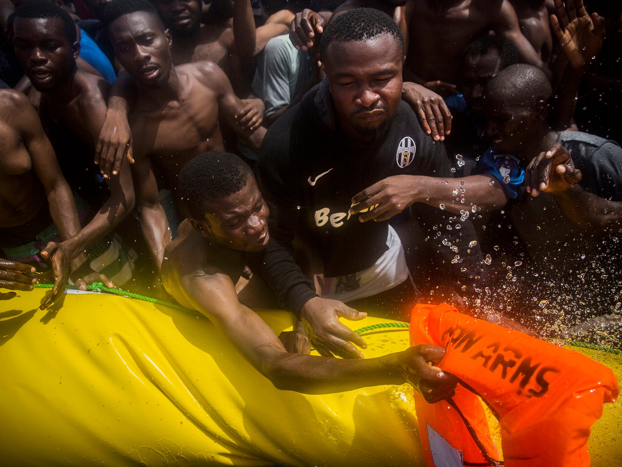 Migrants receive life jackets as workers from Proactive Open Arms pull alongside their dinghy about 15 miles north of Sabratha, Libya