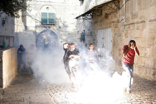 Palestinians scatter as a stun grenade explodes outside the Haram al-Sharif compound in Jerusalem