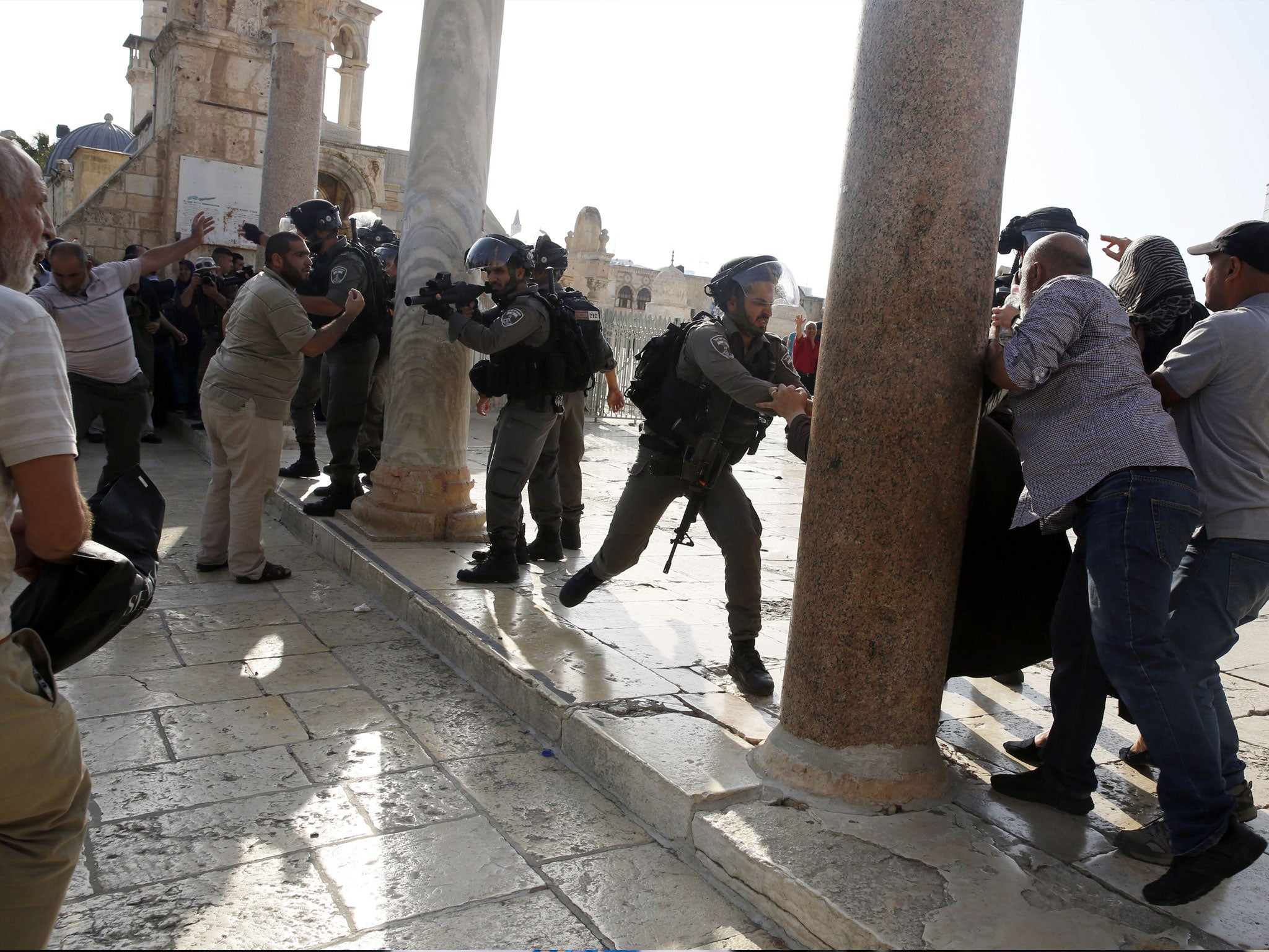 An Israeli police officer aims his weapon at Palestinians during clashes at the Al Aqsa Mosque