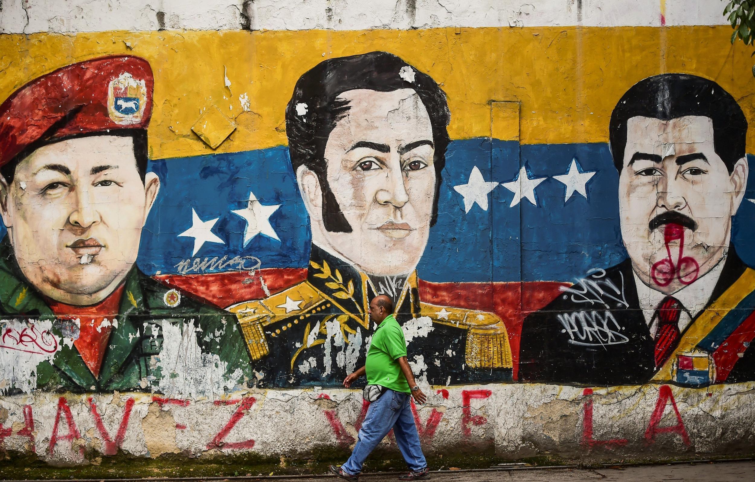 Graffiti depicting Hugo Chavez, revolutionary leader Simon Bolivar and Nicolas Maduro (l-r) which has been defaced