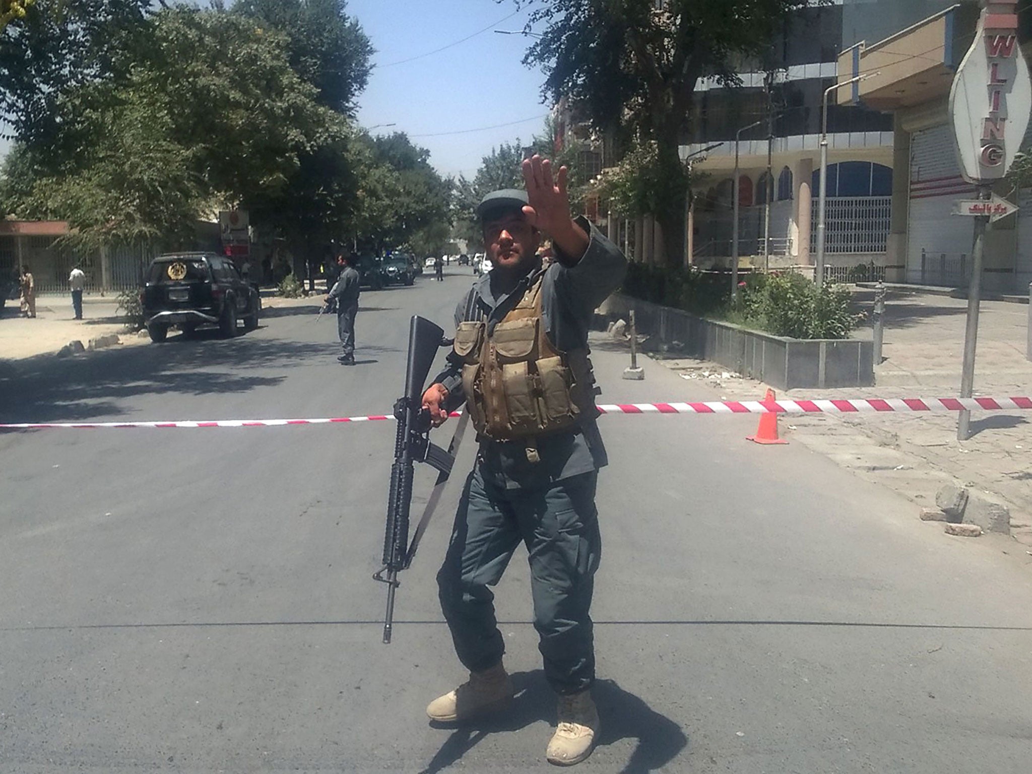 An Afghan policeman sets up a perimeter at the site of the explosion in Kabul