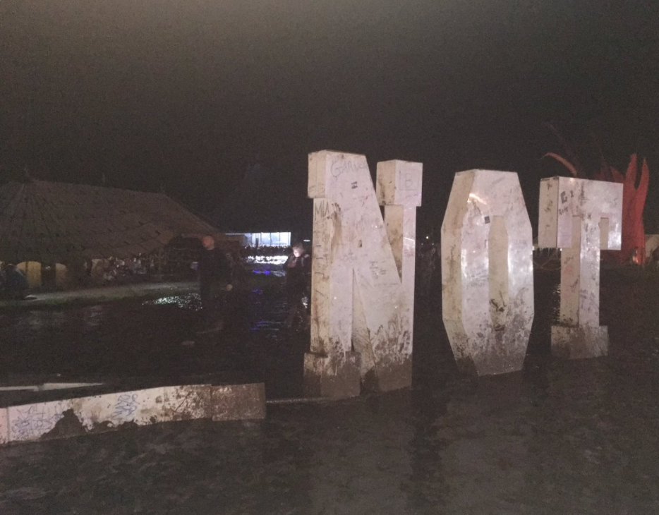 A sign sits in mud at the festival after organisers asked festival-goers to leave for their own safety