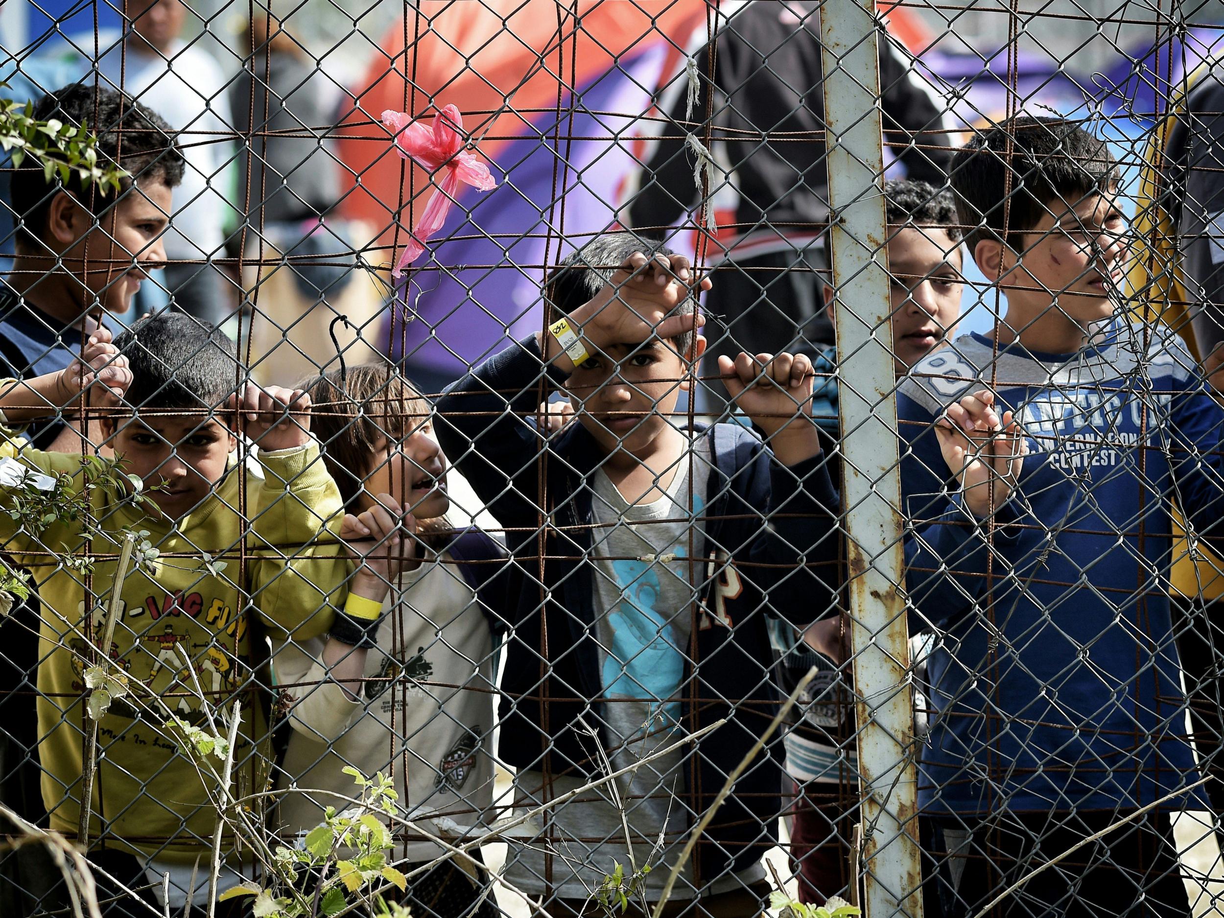 Children stand behind a fence inside the Moria migrant camp transformed in police-run detention facility in Mytilene, on Lesbos island