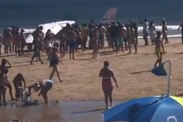 Beachgoers crowded around the light aircraft after it crash landed on the busy beach