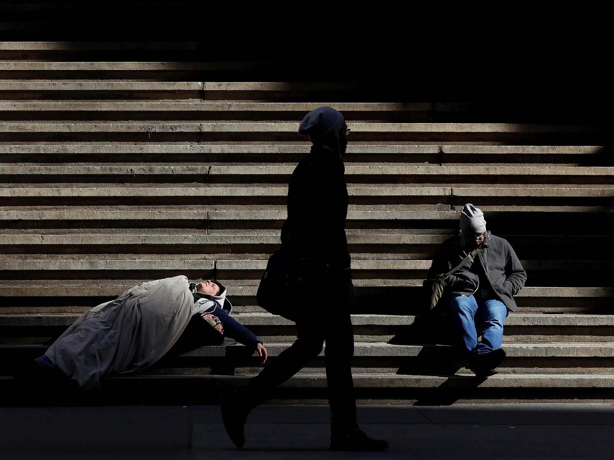 A homeless person sleeps on the steps of Federal Hall in Wall Street