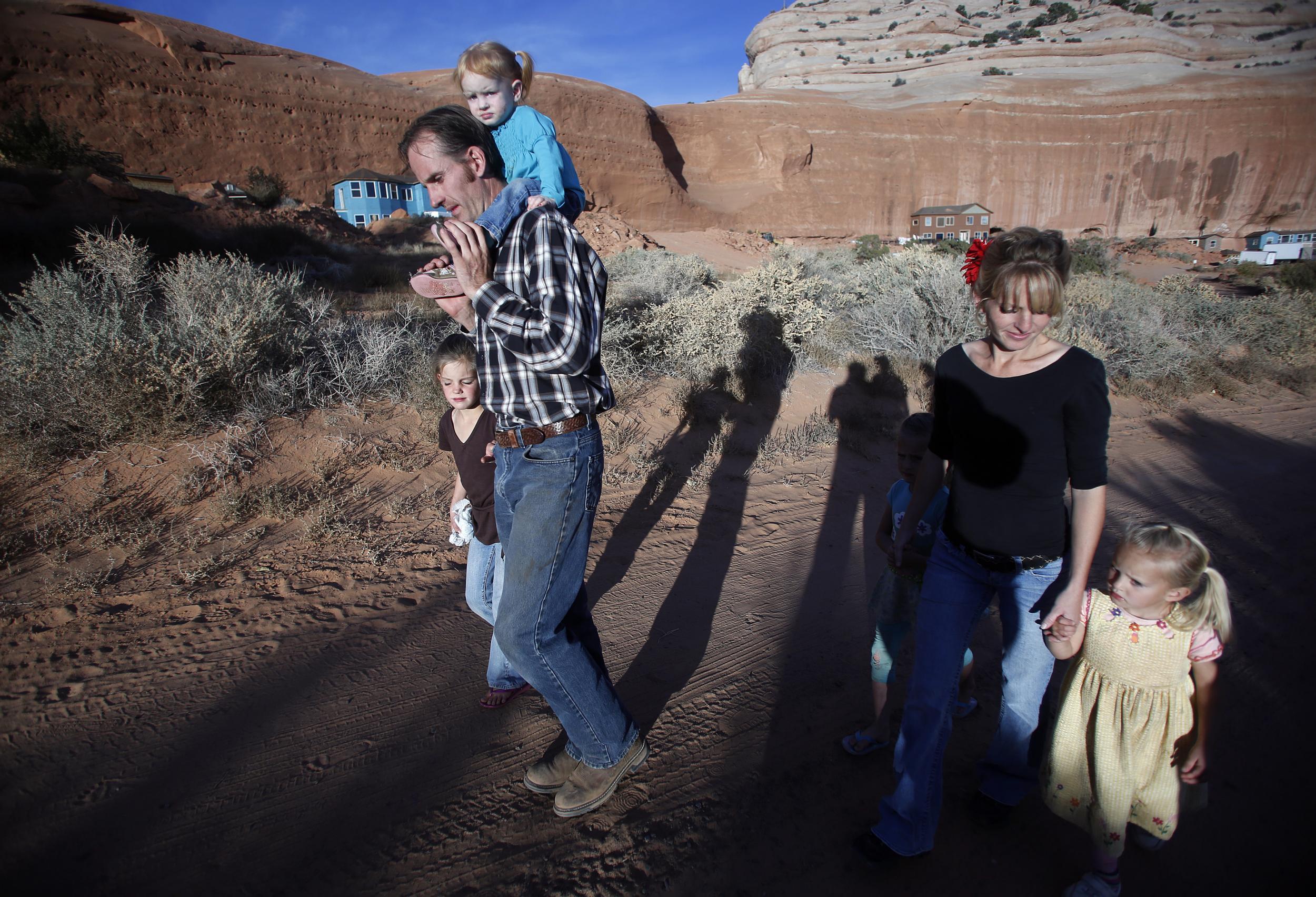Enoch Foster, a fundamentalist Mormon practicing polygamy, walks with his first wife Catrina Foster and several of his 13 children