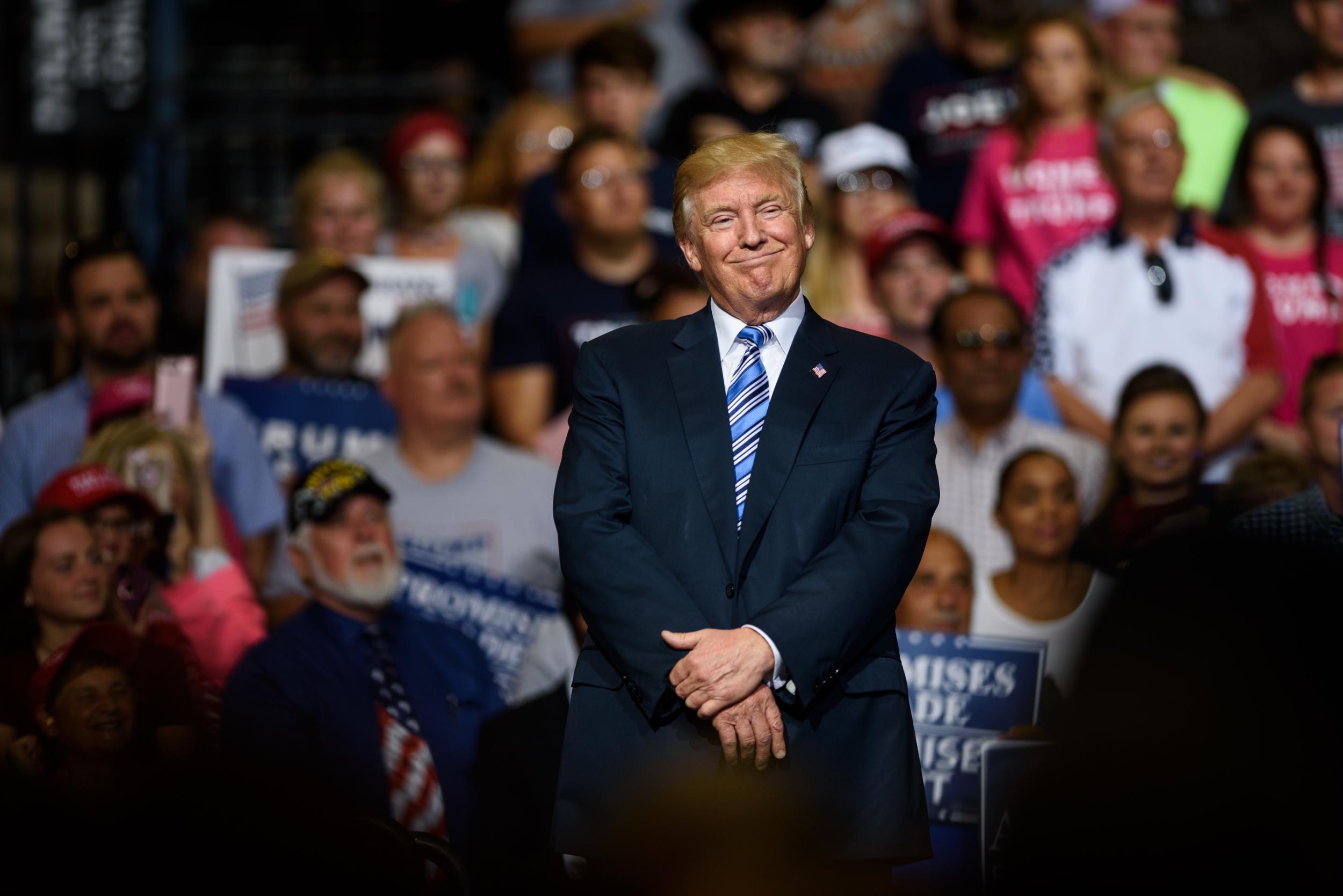 President Donald Trump listens to West Virginia Governor Jim Justice speak at the President's campaign rally