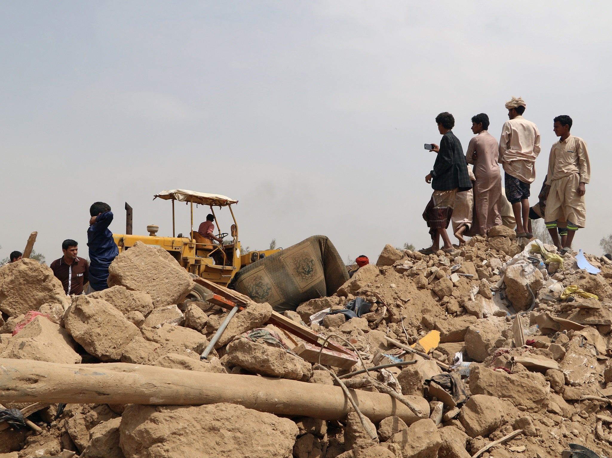 People stand on the debris of a house at the site of a Saudi-led air strike on an outskirt of the northwestern city of Saada