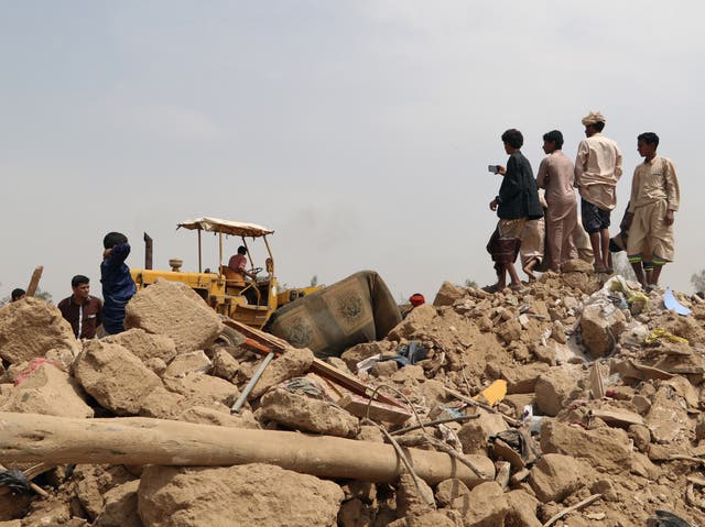 People stand on the debris of a house at the site of a Saudi-led air strike on an outskirt of the northwestern city of Saada