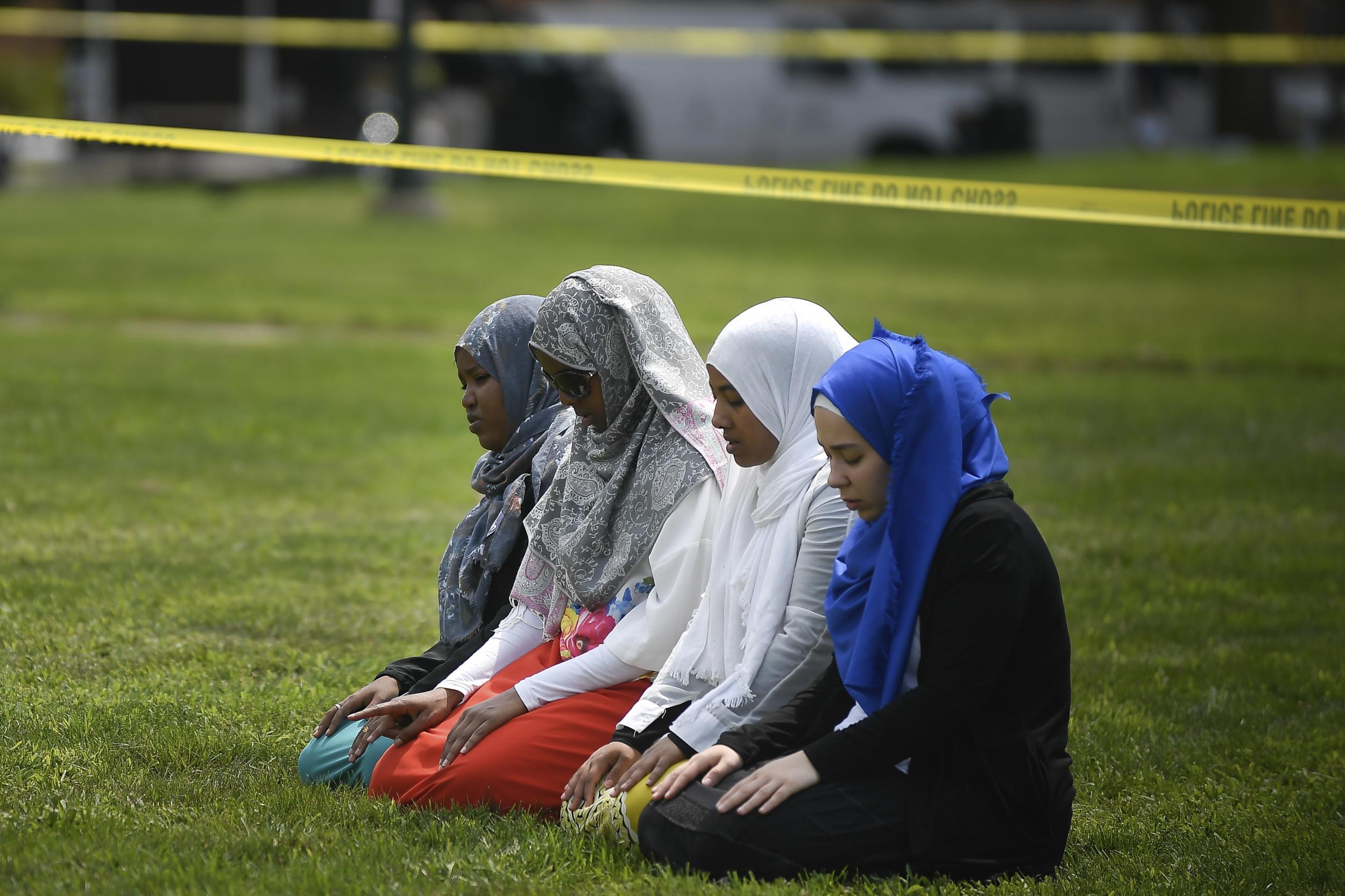 A group of women take part in afternoon prayers led by Dar Al Farooq Islamic Center Executive Director Mohamed Omar outside the police tape surrounding the center