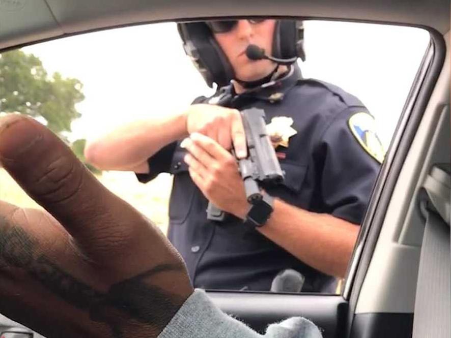 A still from a video apparently recorded by a woman in the car as the male passenger expresses incredulity the officer has drawn his gun