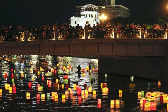 People at Hiroshima Peace Memorial Park, western Japan, watch floating paper lanterns on the Moyasu River, placed to comfort souls of the atomic bomb’s victims.