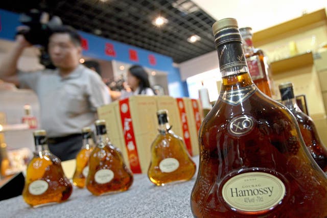 Visitors walk past counterfeit liquor on display at the Beijing administration for industry and commerce center for food safety test in Beijing