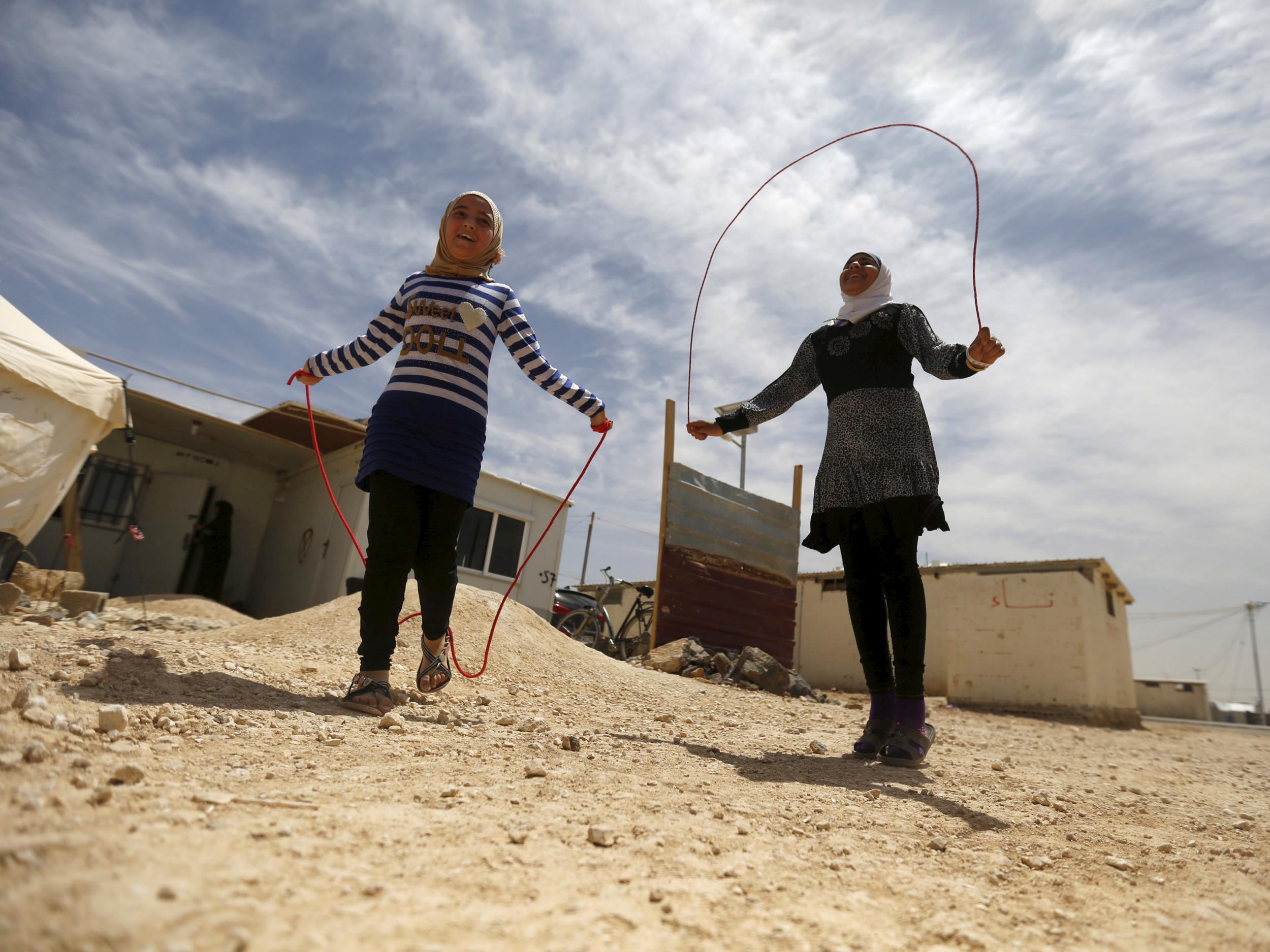 Syrian refugee Omayma al Hushan (left) plays with her friend in the Al Zaatari refugee camp in the Jordanian city of Mafraq