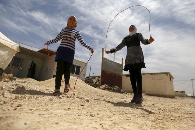 Syrian refugee Omayma al Hushan (left), 14, who launched an initiative against child marriage among refugees, plays with her friend outside their residence in Al Zaatari camp in the Jordanian city of Mafraq