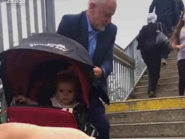Jeremy Corbyn helping woman up the stairs with a buggy