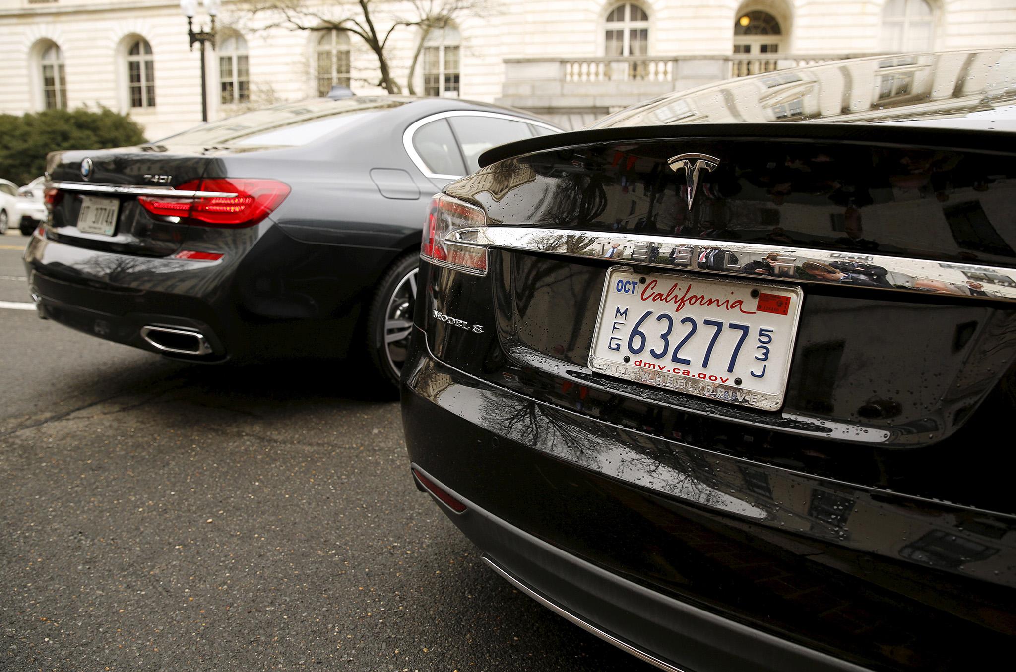 A BMW 740i is self-parked next to a Tesla S sedan via a remote control key. BMW wants to streamline engineers to