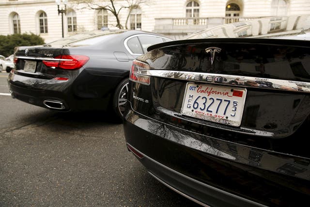 A BMW 740i is self-parked next to a Tesla S sedan via a remote control key. BMW wants to streamline engineers to 