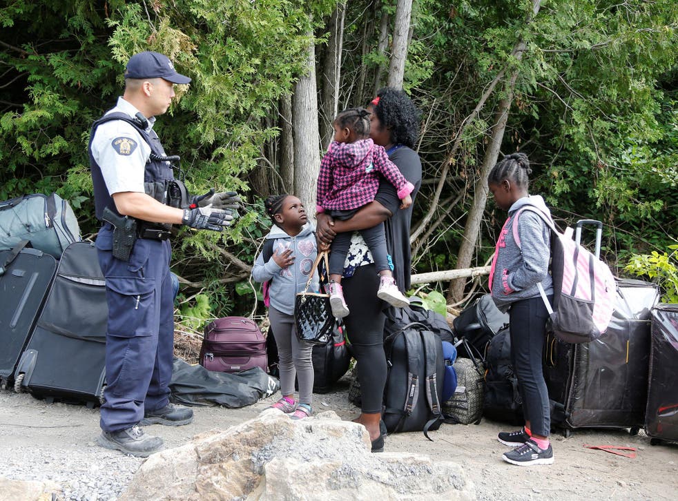 A family who identified themselves as from Haiti are confronted by a Royal Canadian Mounted Police (RCMP) officer as they try to enter into Canada the US