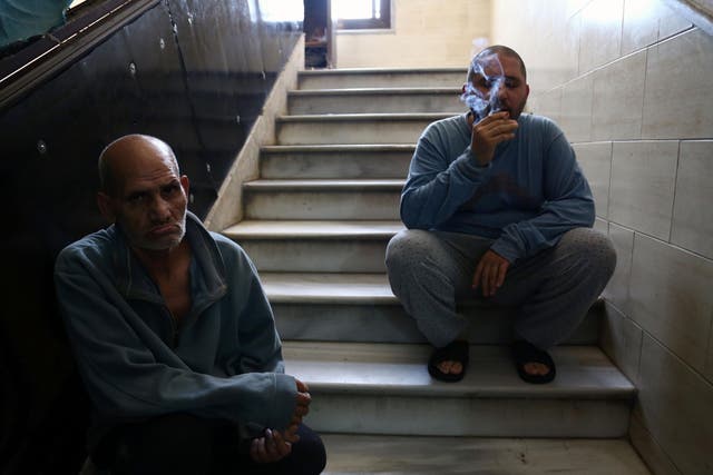 A Syrian patient smokes a cigarette as he sits on a staircase with another man at a mental health clinic - the sole such facility in the rebel-held north of Syria - in the town of Azaz, near the border with Turkey, on 6 July 2017
