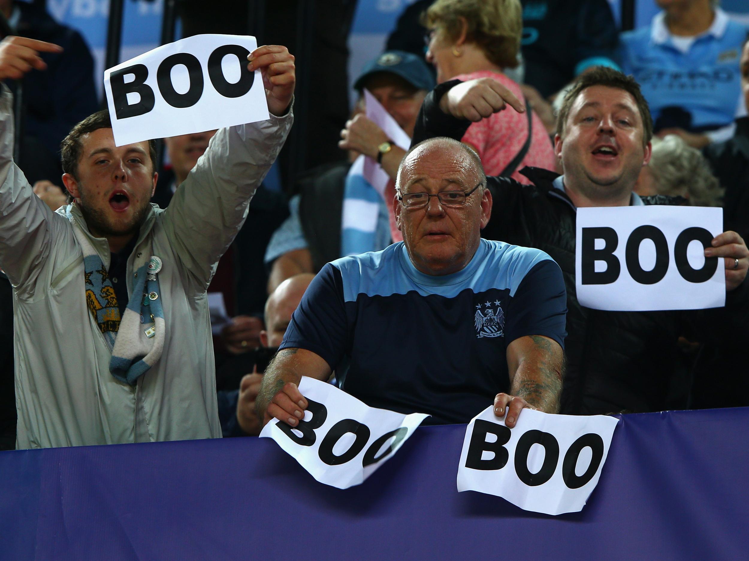 Manchester City fans hold up 'boo' signs ahead of a Champions League clash against Sevilla