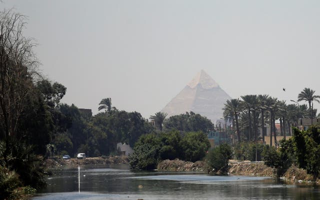 The Pyramid of Khufu, the largest of the Giza pyramids, seen behind a canal which flows into the River Nile on the outskirts of Cairo