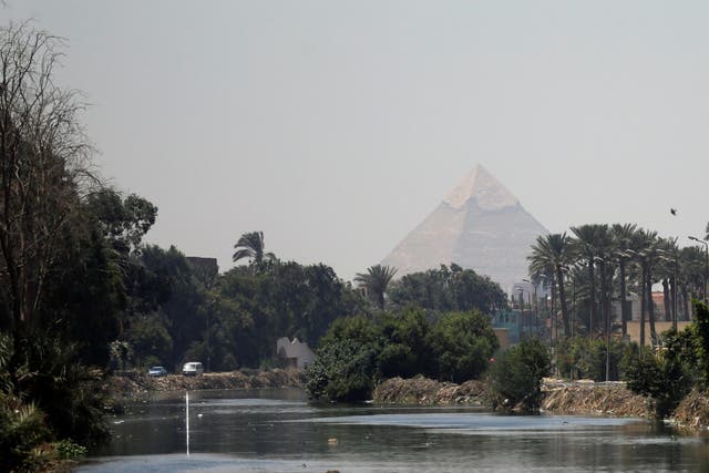The Pyramid of Khufu, the largest of the Giza pyramids, seen behind a canal which flows into the River Nile on the outskirts of Cairo