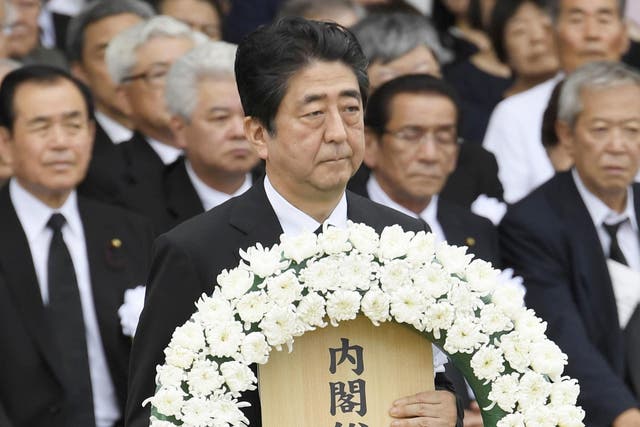 Japan's Prime Minister Shinzo Abe offers a wreath at Nagasaki Peace Park in Nagasaki, southern Japan during a ceremony to mark the 72nd anniversary of the world's second atomic bomb attack over the city