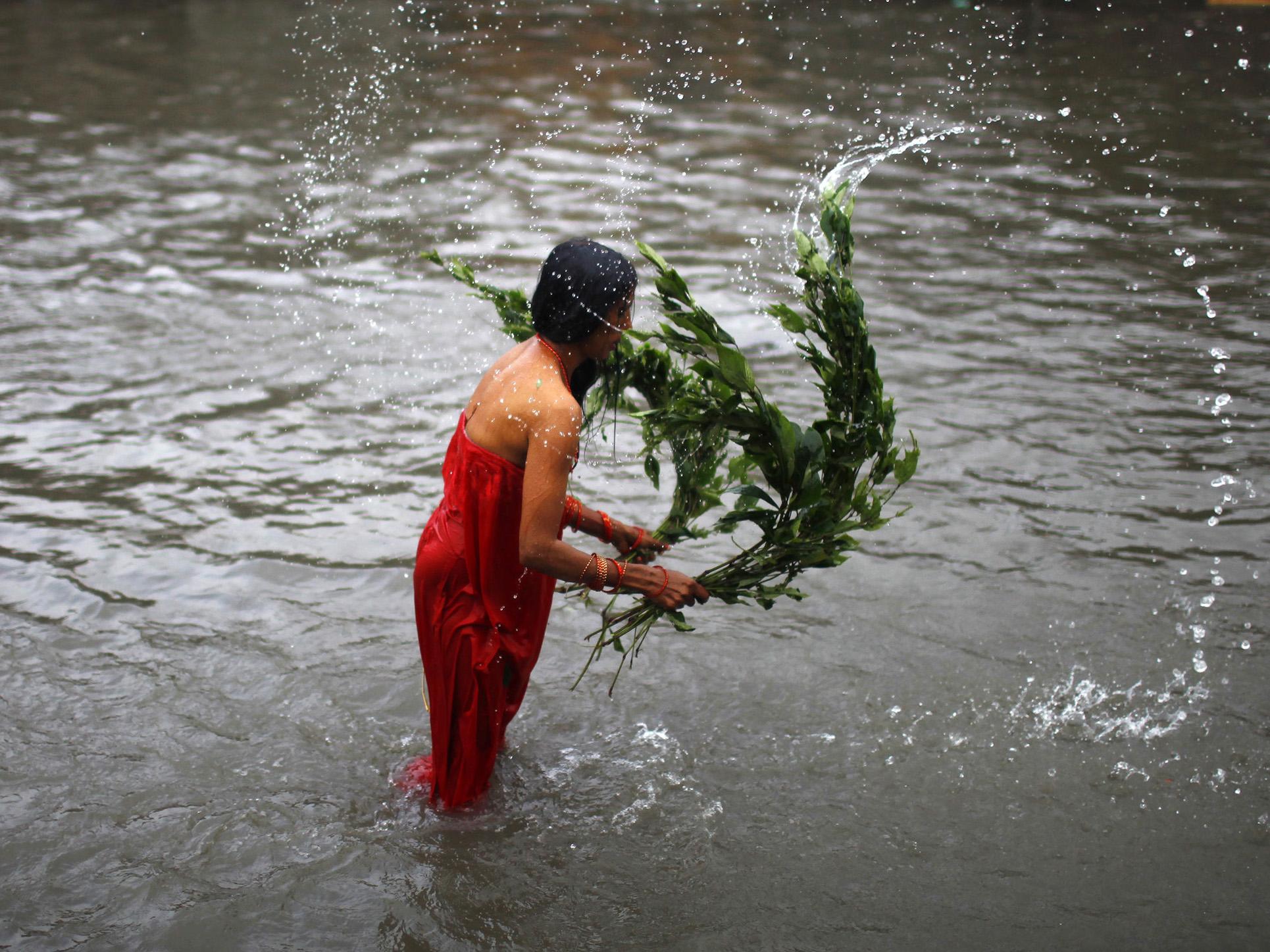 A Nepalese woman lashes herself with the leaves of an Aghada herb as part of a ritual in the Bagmati River during Rishi Panchami, a day when Hindu women perform rituals to wash away sins committed during their menstruation period
