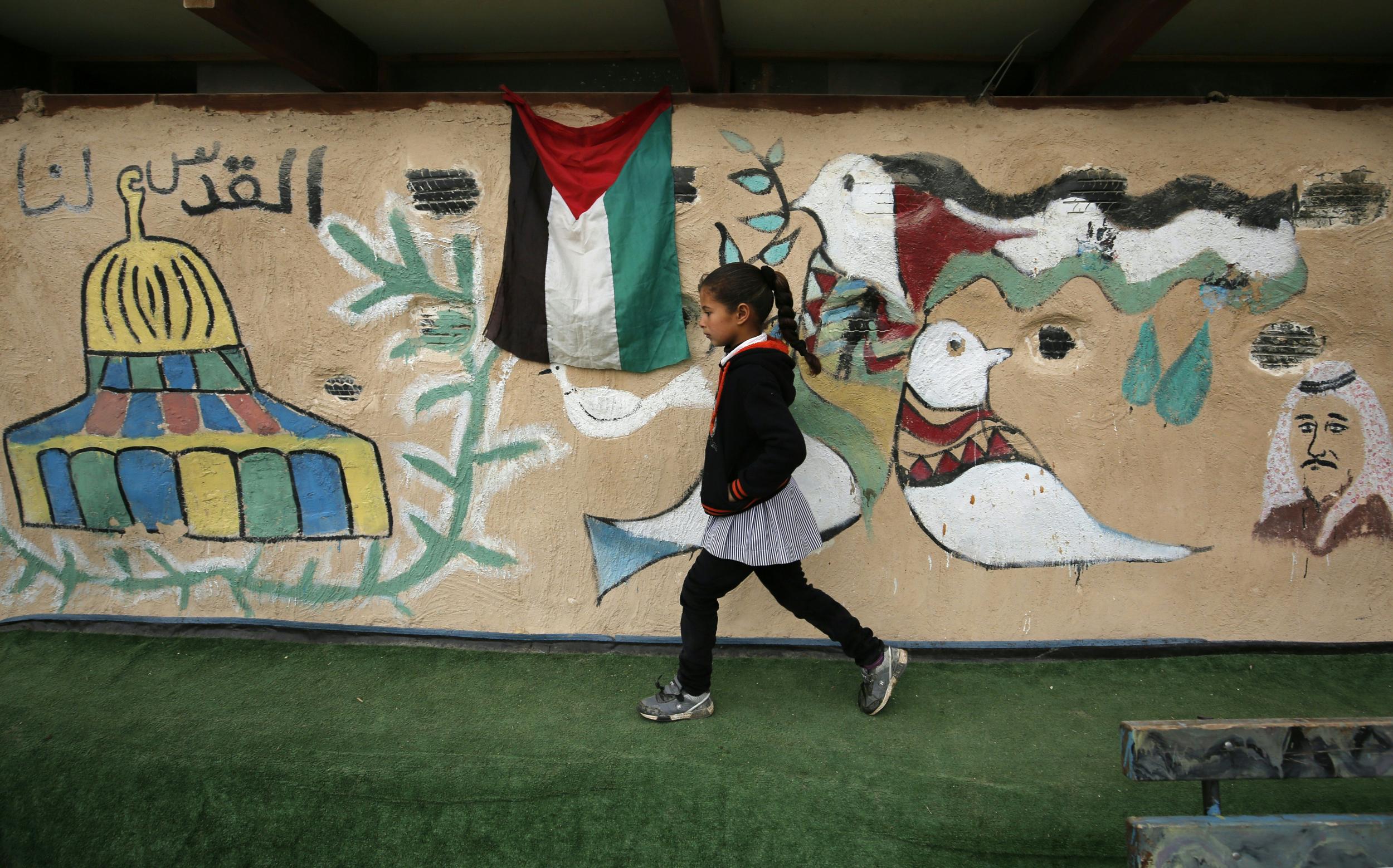 A Bedouin student walks past a mural at her primary school in the Palestinian Bedouin village of Khan al-Ahmar, in the Israeli-occupied West Bank, during a visit of the Palestinian prime minister on 2 March 2017