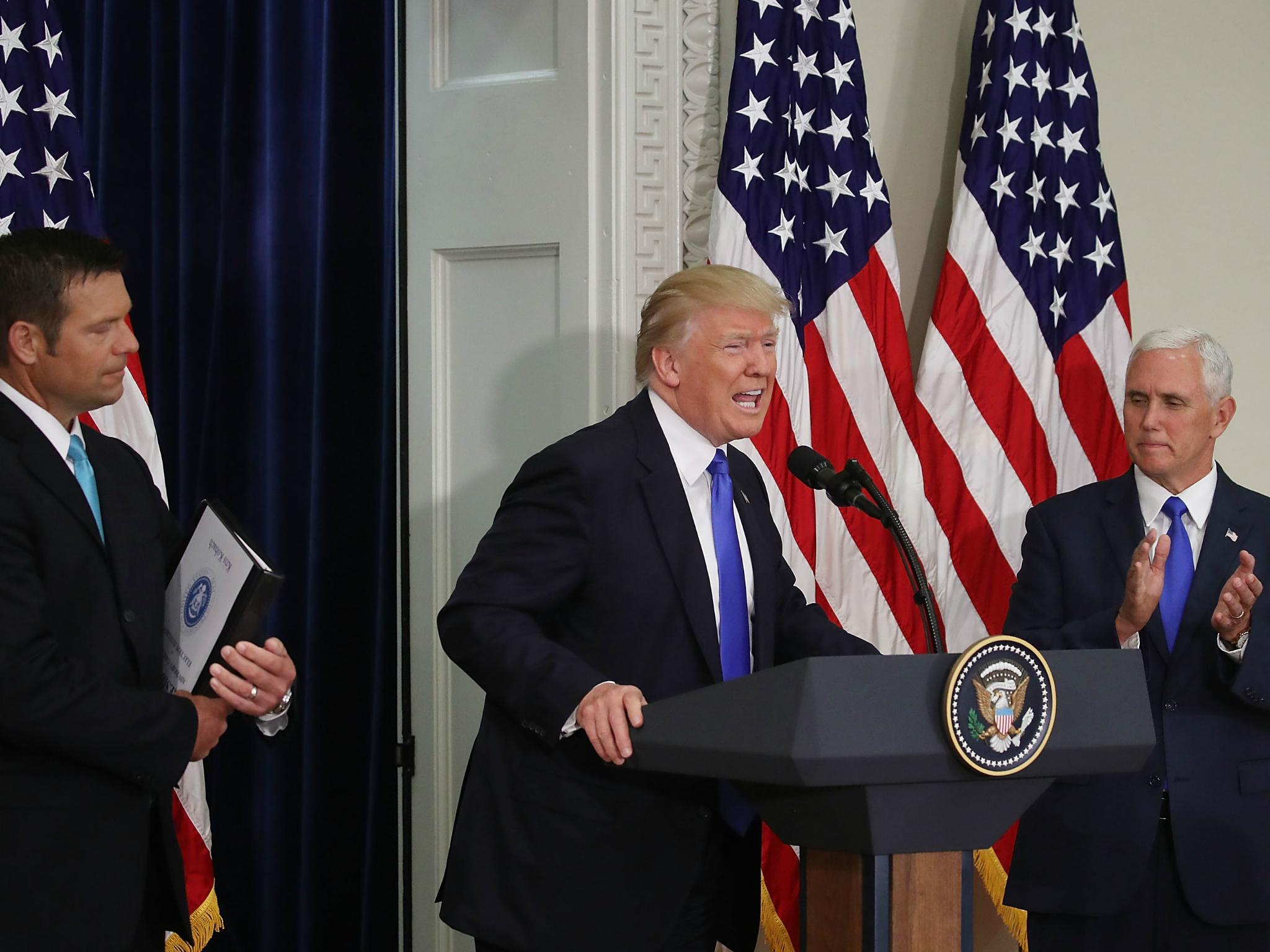 Donald Trump speaks while flanked by Kansas Secretary of State, Kris Kobach and US Vice President Mike Pence during the first meeting of the Presidential Advisory Commission on Election Integrity on 19 July 2017