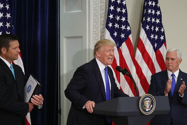 Donald Trump speaks while flanked by Kansas Secretary of State, Kris Kobach and US Vice President Mike Pence during the first meeting of the Presidential Advisory Commission on Election Integrity on 19 July 2017