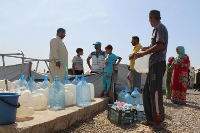Residents displaced by fighting queue for water after a tank is refilled at an IDP camp near Mosul on 9 May, 2017