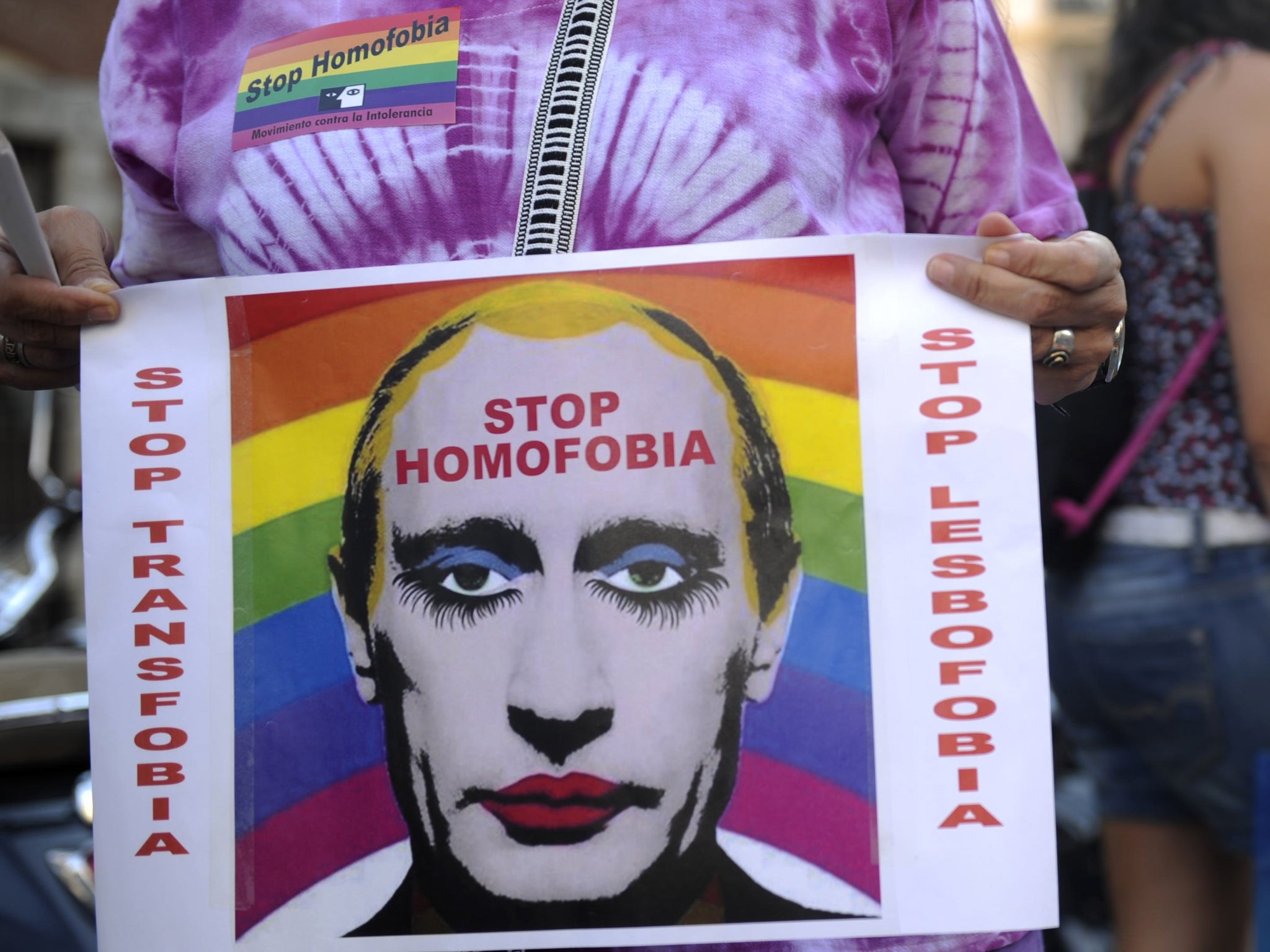 A demonstrator holds a poster depicting Russian President Vladimir Putin with make-up as he protests against homophobia and repression against gays in Russia, in Madrid
