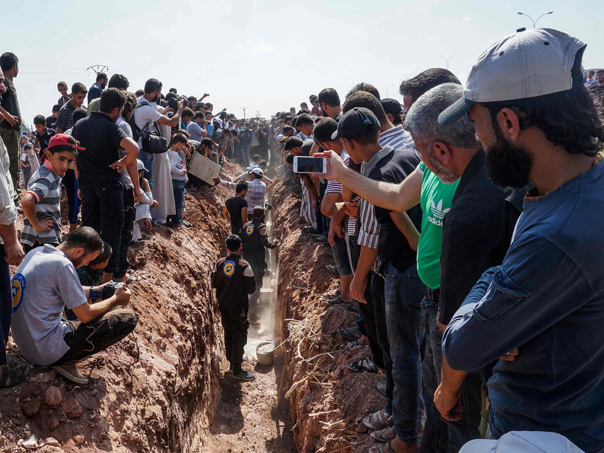 Members of the Syrian civil defence volunteers, also known as the White Helmets, bury their fellow comrades during a funeral in Sarmin, a jihadist-held town nine kilometres east of Syria's northwestern city of Idlib on August 12, 2017, after seven were shot dead early in the morning during a raid on their base, according to the organisation. The Syrian Observatory for Human Rights said the seven volunteers had all been killed by bullets to the head. "Two minibuses, some white helmets and walkie-talkies were stolen," the White Helmets said in statement. It was not immediately clear whether the robbery or the murders were the primary motive for the raid. / AFP PHOTO / OMAR HAJ KADOUROMAR HAJ KADOUR/AFP/Getty Images