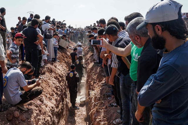 Members of the Syrian civil defence volunteers, also known as the White Helmets, bury their fellow comrades during a funeral in Sarmin, a jihadist-held town nine kilometres east of Syria's northwestern city of Idlib on August 12, 2017, after seven were shot dead early in the morning during a raid on their base, according to the organisation.
The Syrian Observatory for Human Rights said the seven volunteers had all been killed by bullets to the head.
"Two minibuses, some white helmets and walkie-talkies were stolen," the White Helmets said in statement. It was not immediately clear whether the robbery or the murders were the primary motive for the raid. / AFP PHOTO / OMAR HAJ KADOUROMAR HAJ KADOUR/AFP/Getty Images