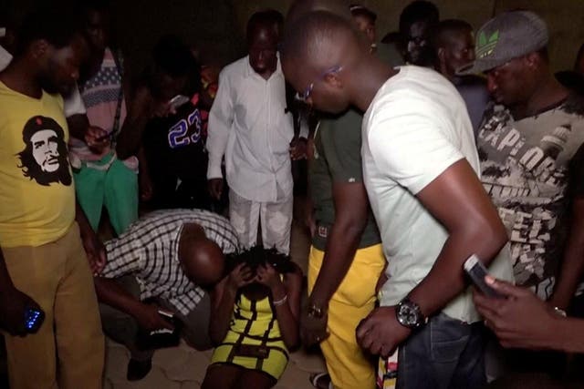 A wounded restaurant customer sits on the ground following an attack by gunmen on a restaurant in Ouagadougou, Burkina Faso