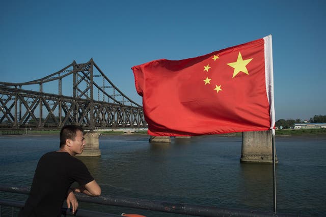 A tourist looks out from the Broken Bridge next to the Friendship bridge on the Yalu River connecting the North Korean town of Sinuiju and the Chinese border city of Dandong