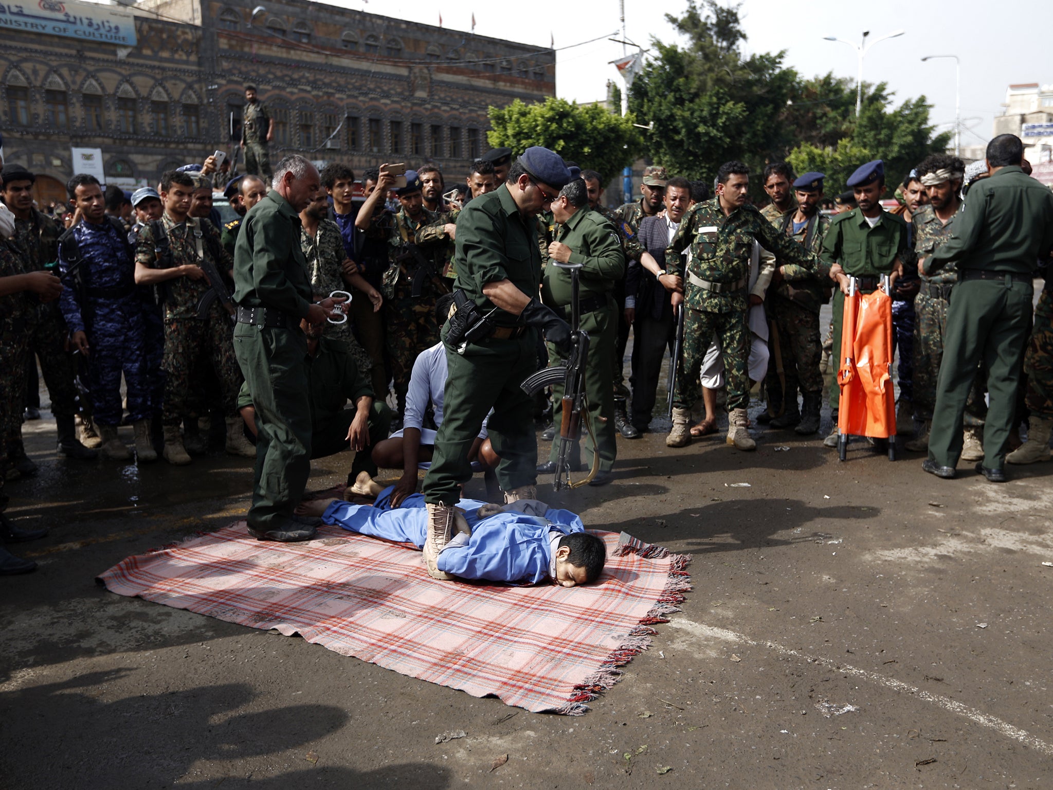 A Yemeni police officer prepares to execute 22-year-old Hussein al-Saket in front of a crowd of onlookers in the capital Sanaa