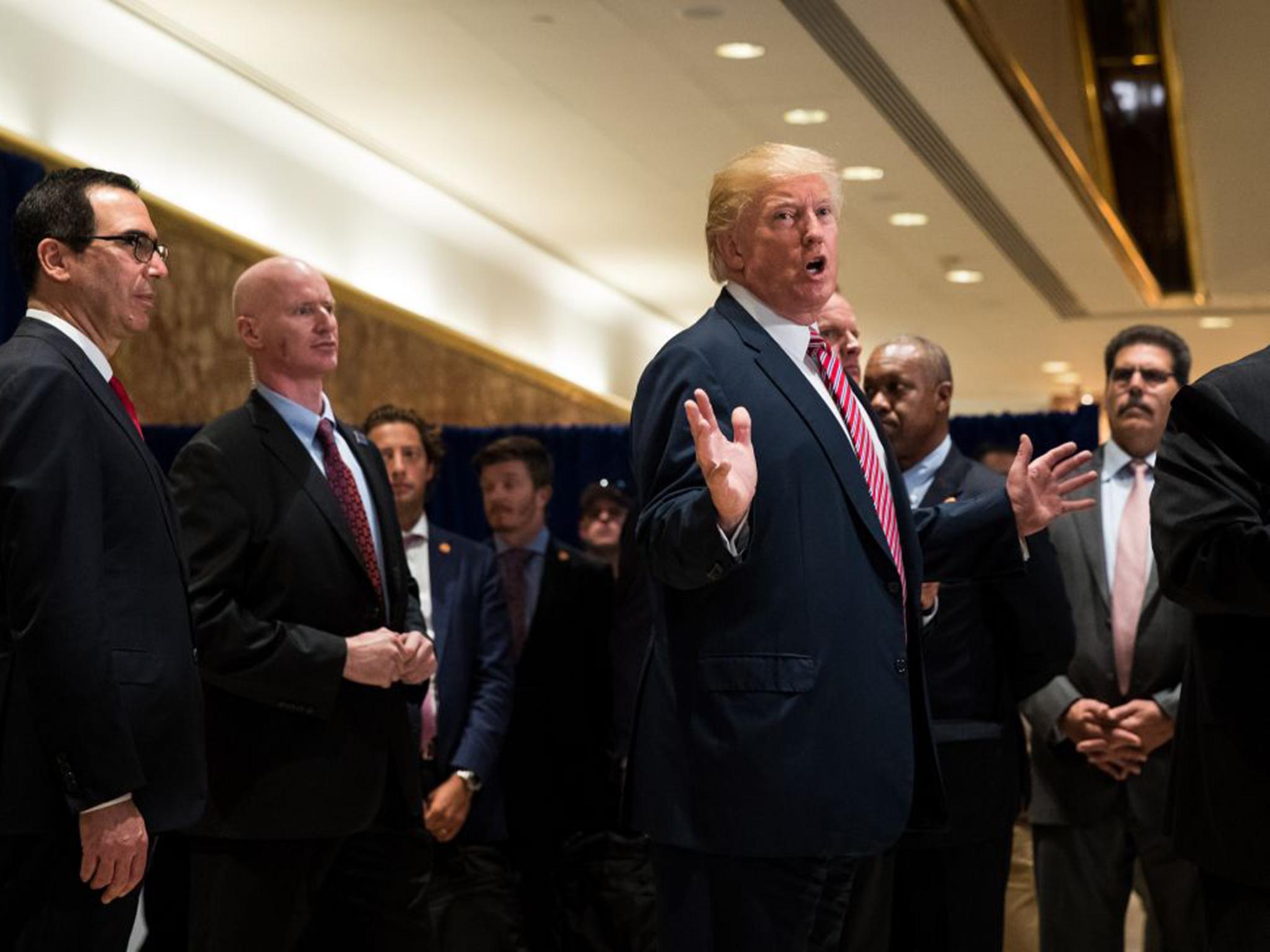 US President Donald Trump speaks to reporters on his way out of the lobby following a meeting on infrastructure at Trump Tower