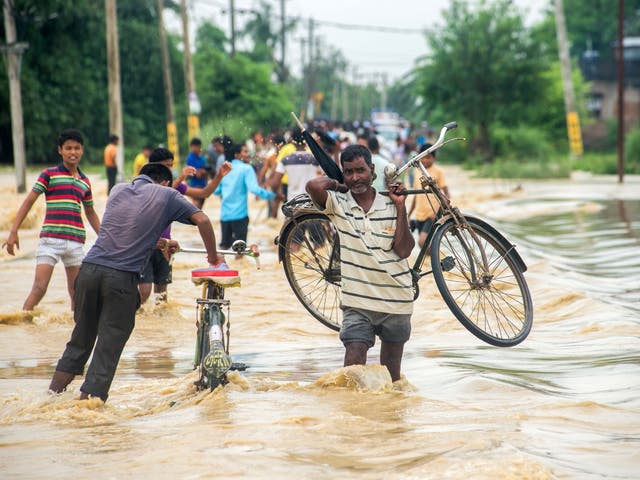 Nepali residents, one carrying a bike, fight floodwaters in the Birgunj Parsa district, some 200km south of Kathmandu