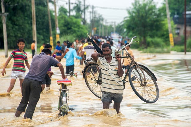 Nepali residents, one carrying a bike, fight floodwaters in the Birgunj Parsa district, some 200km south of Kathmandu
