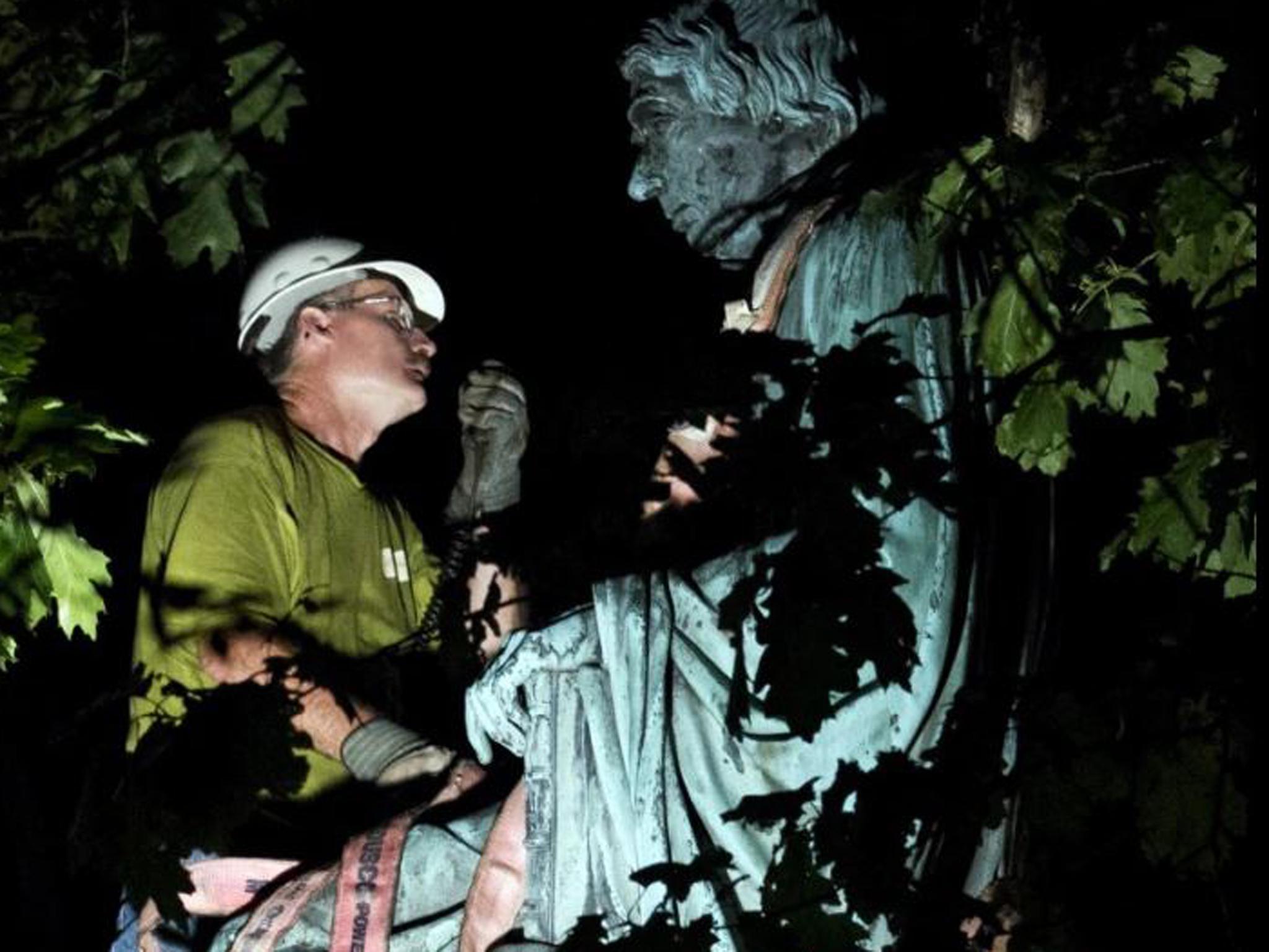 A worker dismantles the statue of Supreme Court Justice Roger B. Taney outside the Maryland State House in Annapolis