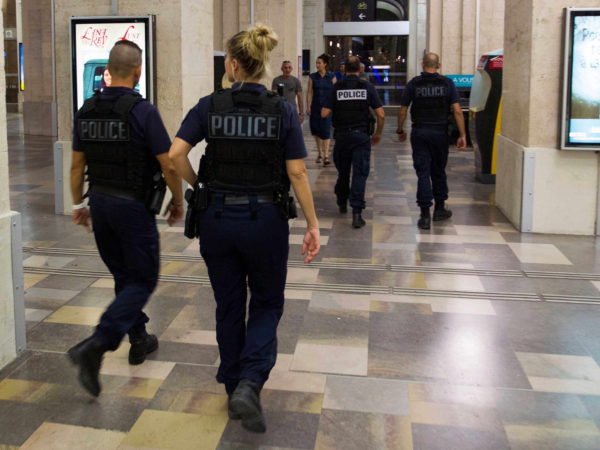 Passengers and police officers walk in the train station of Nimes after it was reopen on August 19, 2017